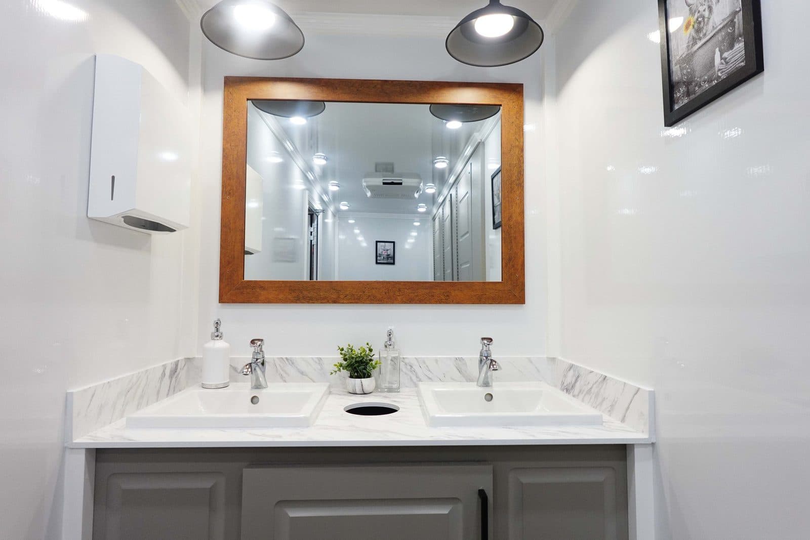 Marble-look double vanity with framed mirror and pendant lights inside a Trailer Bash Events luxury restroom trailer